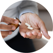 A close-up of hands taking out two white botanical extracts plant based pills from a bottle